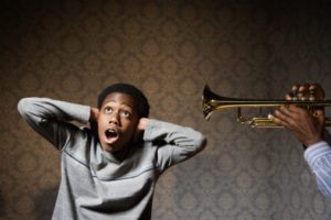 African man playing trumpet in boy's ear